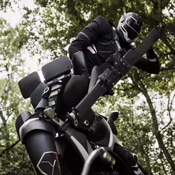 the person is wearing black and riding a motorcycle in the woods