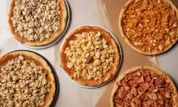 some pies sitting on a table with toppings