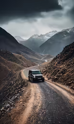 the vehicle drives on a dirt road with mountains in the background