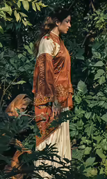 a woman is standing amongst leaves and bushes