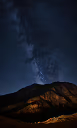 stars are shown in the night sky above the hills