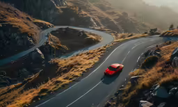 a red car travels along a winding mountain road