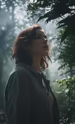 a woman standing in a forest surrounded by trees