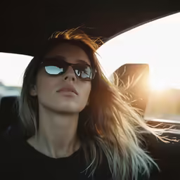 a girl is wearing sunglasses while sitting in the back of a car