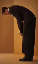 a man in a suit and shoes with one foot on the ground