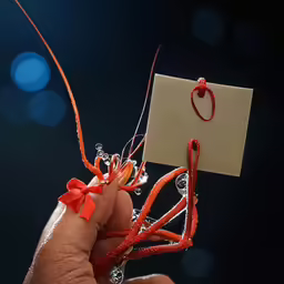 a person holds up a red string and paper