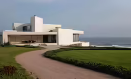 a large white house in front of the ocean