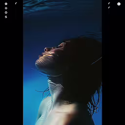 a person swims beneath the water in a photo,a woman in a body of water has her head above water