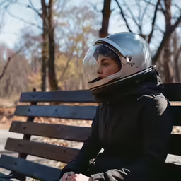 a person in a motorcycle helmet sitting on a park bench