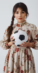 young woman holding soccer ball in dress