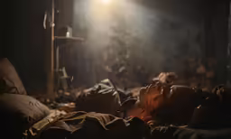 a woman lies in bed covered with brown blankets