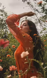 a beautiful woman wearing an orange shirt sitting in the grass