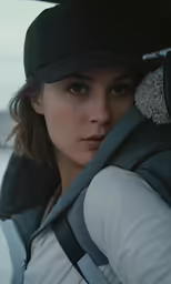 a woman wearing a cap and vest, carrying a backpack
