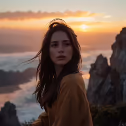 a woman sits in front of the ocean at sunset