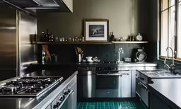 a kitchen has all stainless steel appliances and blue tiles