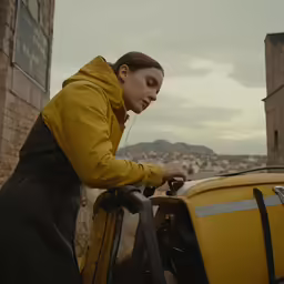 woman in yellow jacket leaning on a yellow back pack