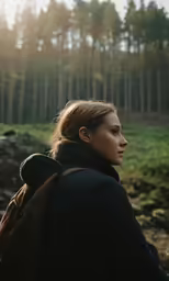 a young girl in a jacket and backpack stares off into the distance