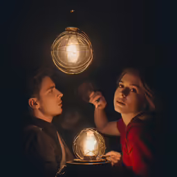 the two people are lighting a light bulb