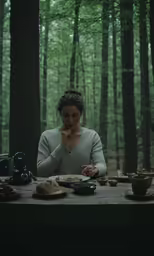 a woman is eating in the woods with tea