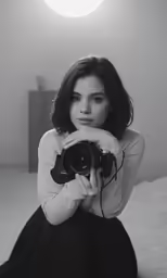 a woman in black and white holding up a camera
