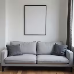 a white couch with gray pillows and a black framed picture