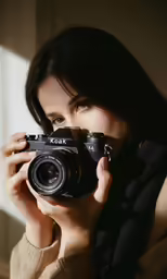 woman in a brown sweater taking a photo with an old camera