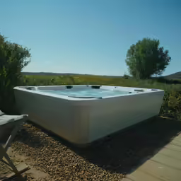 a large jacuzzi sits in the grass on the side of a wooden deck