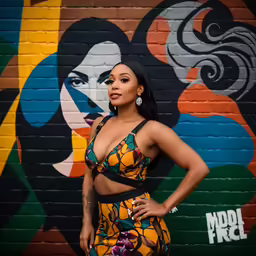 a woman in colorful outfits poses in front of a graffiti - covered wall
