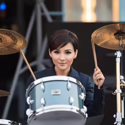 a woman holding drums and posing for the camera