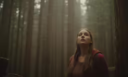 a woman standing in front of tall trees