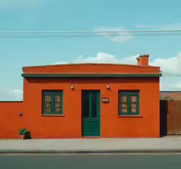 a red house with green shutters sits next to a sidewalk