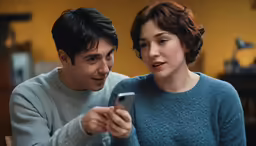there is a woman and a man that are looking at something on a cellphone