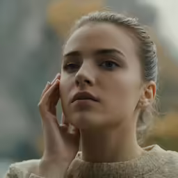 a woman holding her hands behind her ear