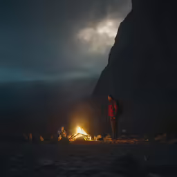 people sitting around a campfire while the sun is set