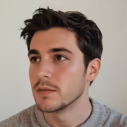 a man in gray shirt wearing a tie and sweater