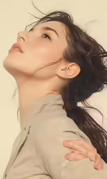 a woman with a ponytail holding her head with both hands and looking to the sky