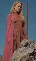 a female dressed in a dress and jacket with a sword