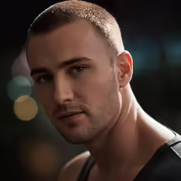 a man with a shaved head and black vest
