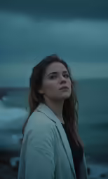 a woman stands on the beach in front of a stormy sea