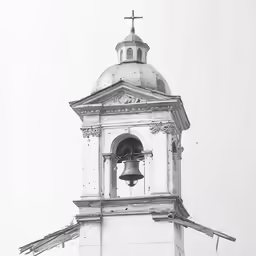 an old white church tower with a bell