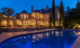 a mansion with a swimming pool surrounded by trees