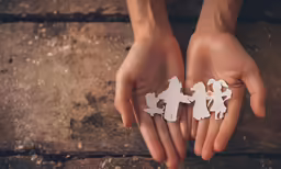 two hands with some cut out pieces of people on them