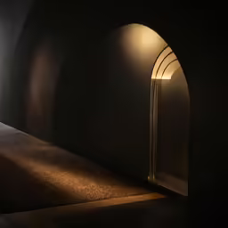 a dark room with an open archway leading into the light