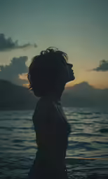 a woman is standing alone in front of the ocean