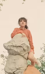 a girl sits on top of a stone sculpture