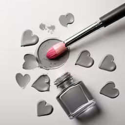 make up brush and lipstick on table surrounded by hearts