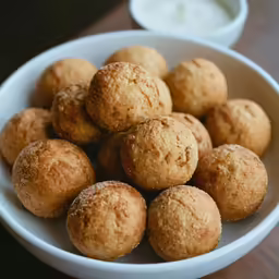 a bowl filled with muffins on top of a wooden table