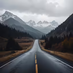 a long straight road passing by some snow covered mountains