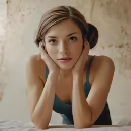 a woman is posing with her hands on her face