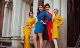 three women in different colors posing outside of building